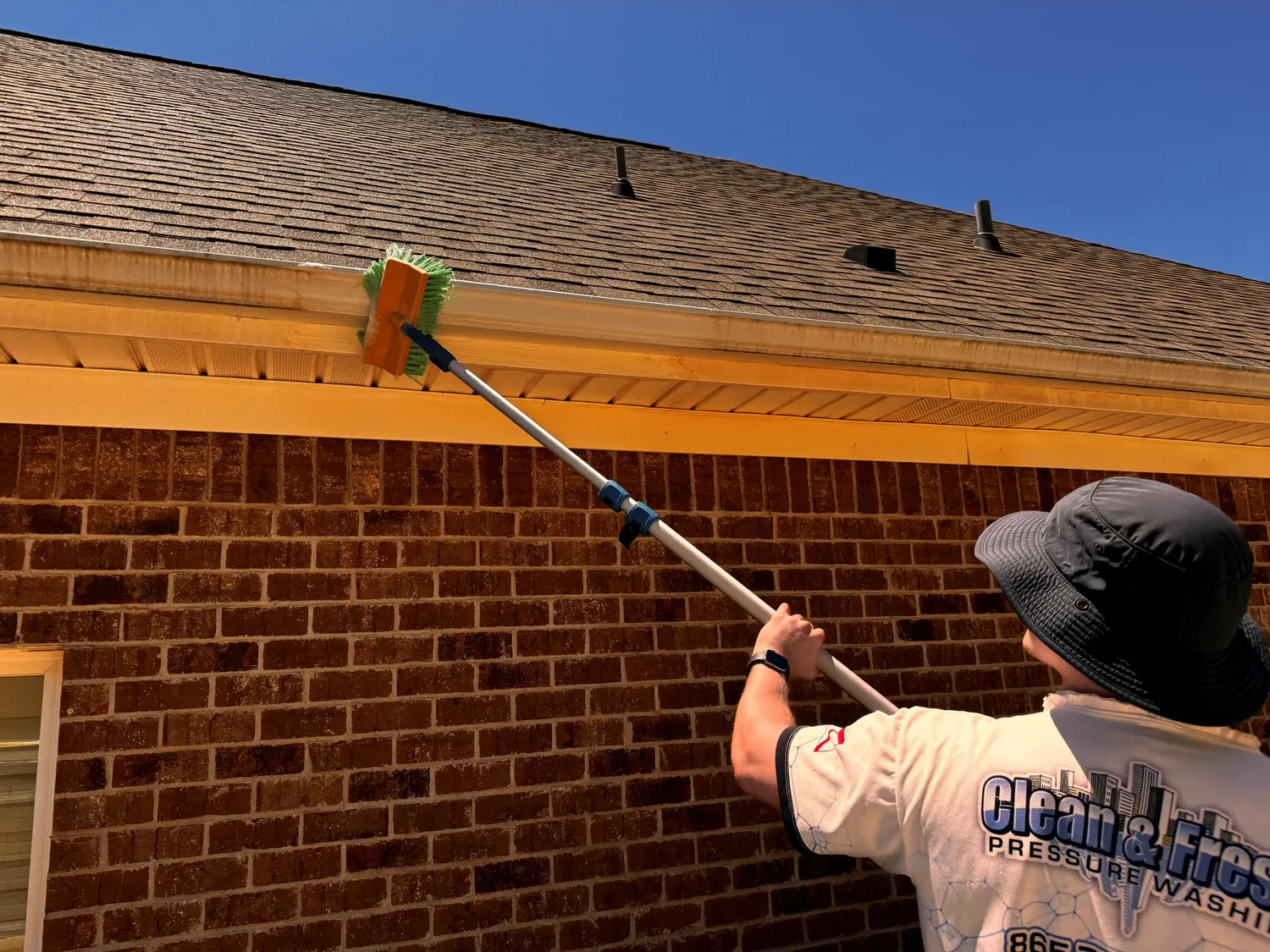 A Clean and Fresh technician brushing the exterior face of a gutter