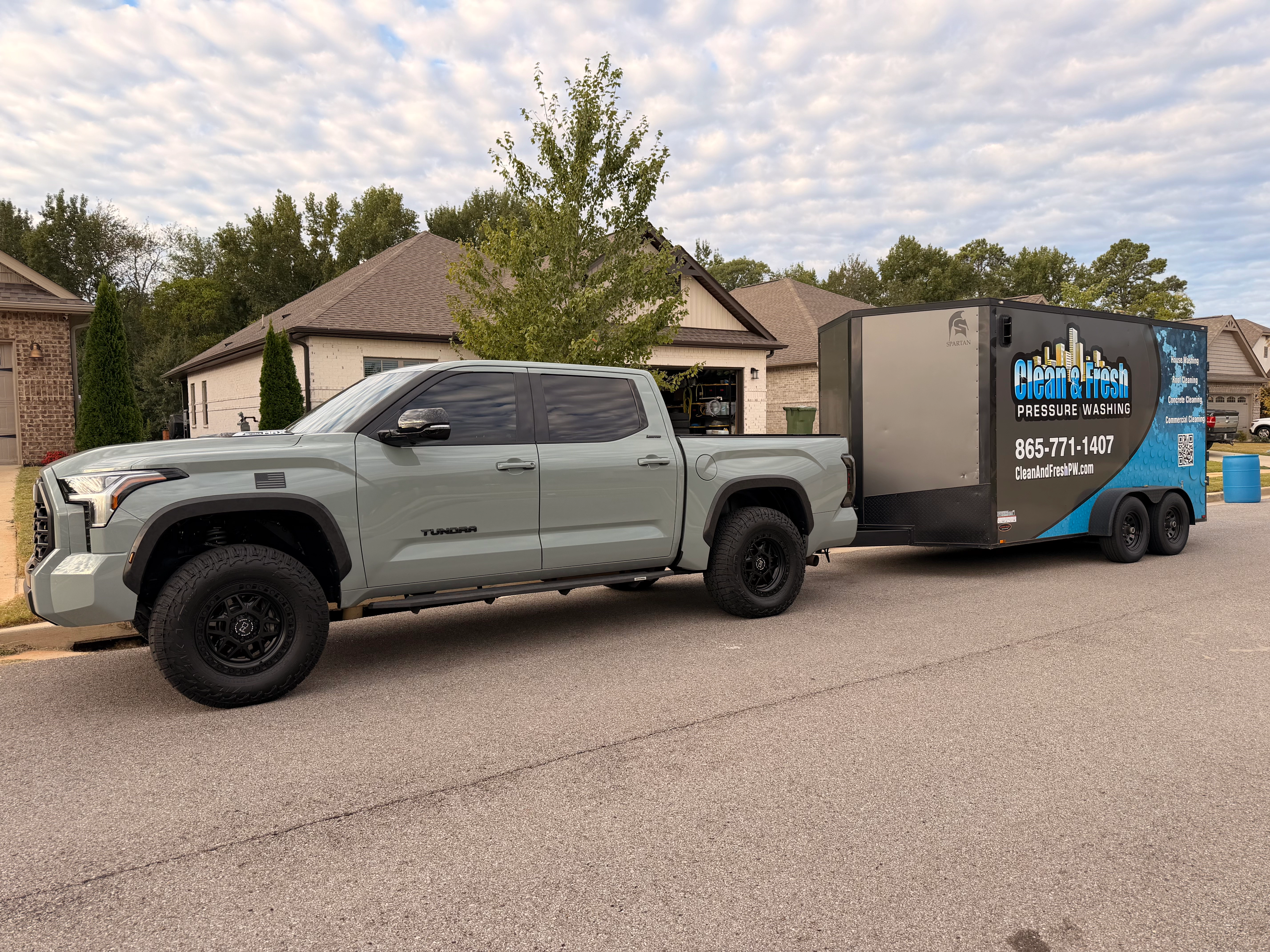 Gray pickup towing the Clean and Fresh enclosed trailer, branded with the logo, phone number and services