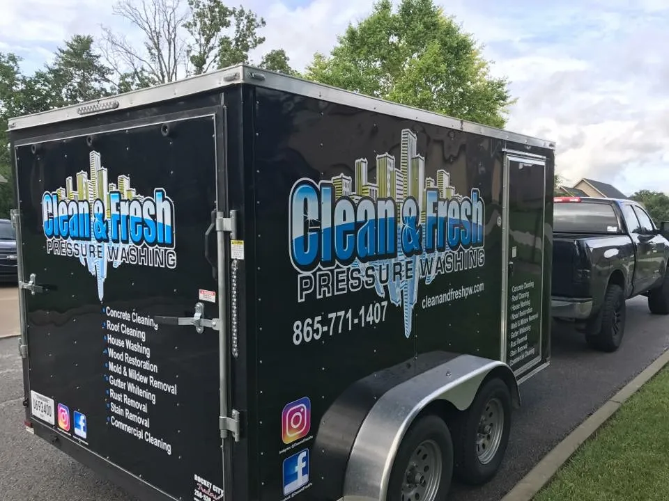 The enclosed trailer wrapped with the Clean and Fresh logo, phone number and list of services, hitched to a black pickup