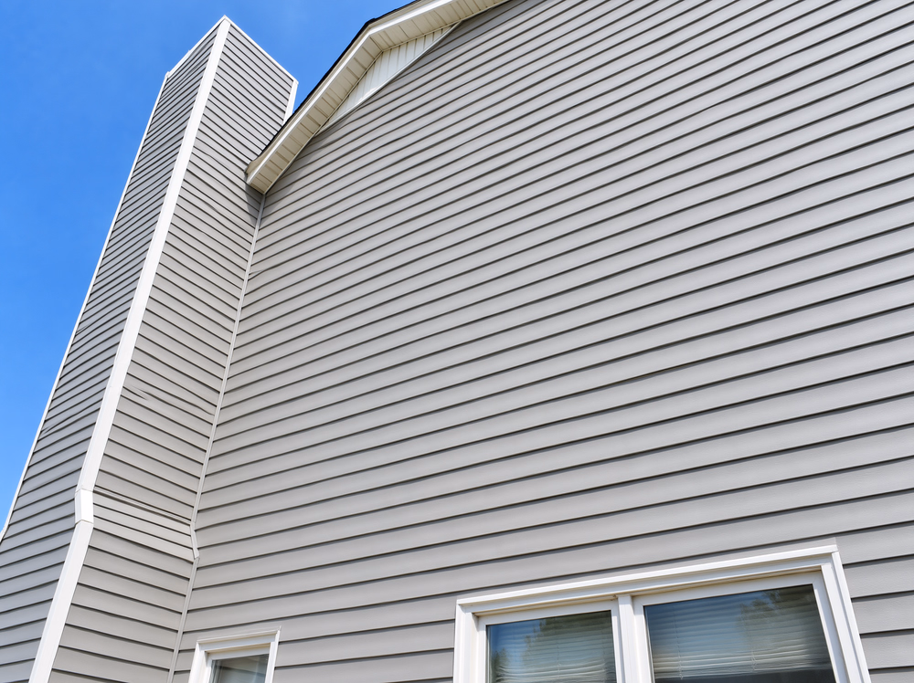 Clean gray lap siding, white roof trim and upper windows viewed from below