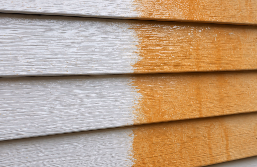 Close view of pale horizontal siding with an irregular transition to orange mineral deposits